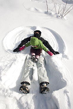 A mother and young daughter play in the snow.