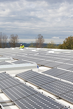 Green energy technician adjusts photovoltaic panels on a roof