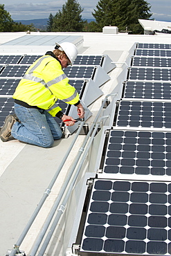 Green energy technician adjusts photovoltaic panels on a roof
