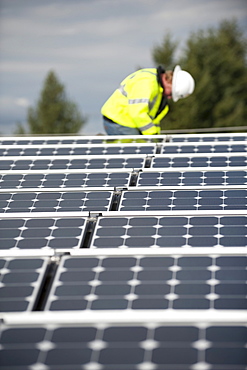 Green energy technician adjusts photovoltaic panels on a roof