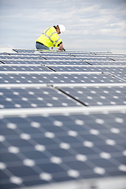 Green energy technician adjusts photovoltaic panels on a roof