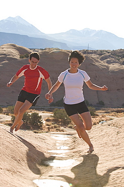 Man and woman  barefoot running in Moab, Utah.