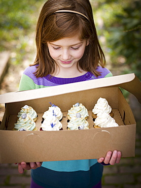 girl holds box of cupcakes