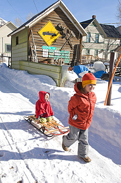 Two young girls playing with a sled in a back alley of Silverton, Colorado.