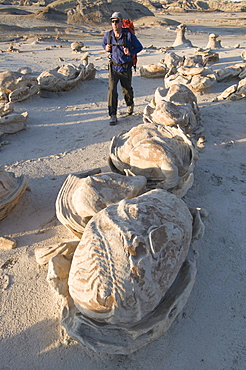 A man hiking and exploring the complex sandstone rock formations at Bisti Badlands outside of Farmington, New Mexico.