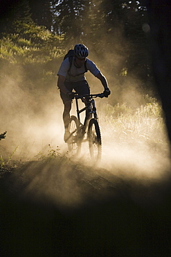 A man mountain biking in the dust.