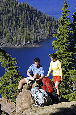 Hikers along cliff trail near lake.