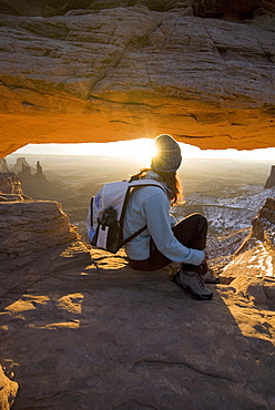 Woman sitting by rock arch.