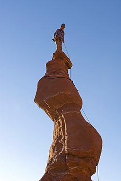 Woman of top of sandstone spire, Fisher Towers, Utah.