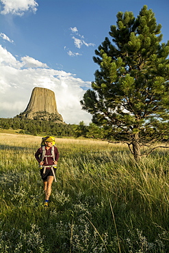 A woman hiking with her backpack below Devil's Tower in Devil's Tower National Monument, Wyoming, Devils Tower, Wyoming, usa