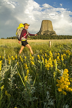 A woman hiking with her backpack below Devil's Tower in Devil's Tower National Monument, Wyoming, Devils Tower, Wyoming, usa