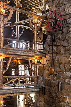 A woman standing next to the intricate log work inside the Old Faithful Lodge in Yellowstone National Park, Wyoming, Yellowstone, Wyoming, usa