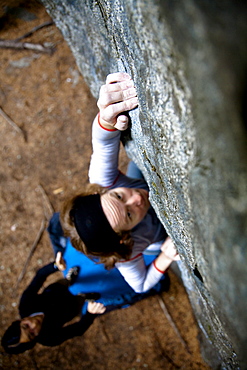 A female rock climber reaches out while on a boulder climb in Pemberton, British Columbia, Canada, Pemberton, British Columbia, Canada