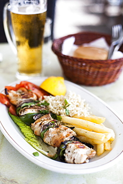 Grilled chicken kebab and a pint of beer at a restaurant in Greece.