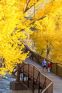 A mother and daughter walking over the Animas River on a bridge on the Animas River Trail in Durango, Colorado.