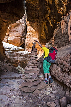 A young girl  backpacking past stone cairns on the Joint Trail in the Needles District of Canyonlands National Park, Monticello, Utah.