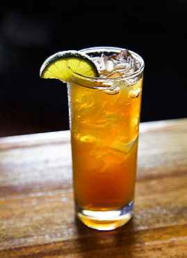 Iced tea with lime sitting on a bar.