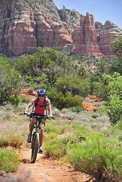 Woman rides the Templeton Trail in South Sedona, Arizona.  Templeton Trail rides over slickrock of the Cathedral Rock with views of Courthouse Butte across the way.