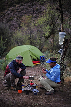 Woman and man backpackers prepare dinner with a camp stove at camp close to Charleboise Springs in La Barge Canyon on the Dutchmans Trail in the Superstition Wilderness Area, Tonto National Forest near Phoenix, Arizona November 2011.  The trail links up with the popular Peralta Trail and offers a spectacular tour through the rugged Sonoran desert.