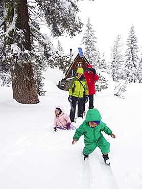 Parents and kids play in fresh snow in front of the Peter Grubb ski hut, Sierra Nevada