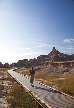 A young woman walks along a boardwalk in Badlands National Park, SD, United States of America