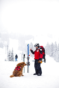 Court Wing, a legendary ski patroller at Steven's Pass, WA with his dog on a snowy day, United States of America