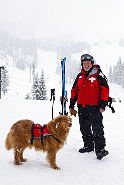 Court Wing, a legendary ski patroller at Steven's Pass, WA with his dog on a snowy day, United States of America