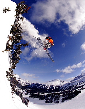 A skier surgically splits the trees and catches some bluebird Canadian air, Canada