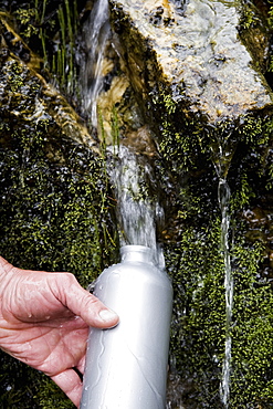 A hiker stops to fill his waterbottle with spring water along the trail, Ecuador