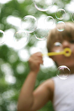 A young boy blows bubbles on his back porch in St. Charles, Missouri on August 3, 2007, United States of America