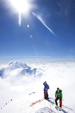 Climbers and rangers Dave Weber and Tom Ditolla are on a snow ridge of the West Rib high on Mount McKinley. Dave is pointing to the summit, Mount Hunter is seen in the background.