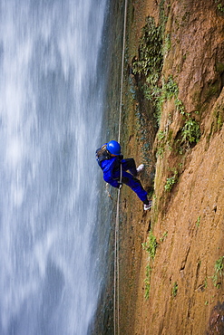 A woman rappelling down next to Deer Creek Falls, Grand Canyon, Arizona.