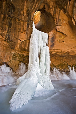 Frozen waterfall coming through a sandstone arch in Utah.