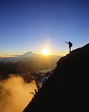 A climber celebrates a beautiful winter day high above the clouds on Goat Mtn, North Cascades, Washington.