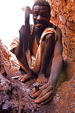 A gold miner works in a shaft using hand tools in Sudan.