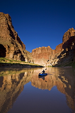 A person paddling an inflatable kayak duckie down the Colorado river, Utah.