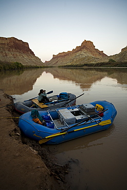 Woman sitting in a raft looking out with binoculars, Colorado river, Canyonlands National Park, Utah.