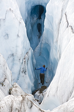 Woman looking into chasm in glacier near McCarthy, Alaska.