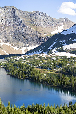 A man stand up paddle boards (SUP) on a calm Hidden Lake in Glacier National Park.