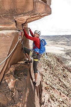 A man rock climbing a desert sandstone tower called Psycho Babble Tower in the Big Gypsum Valley near, Naturita, Colorado.