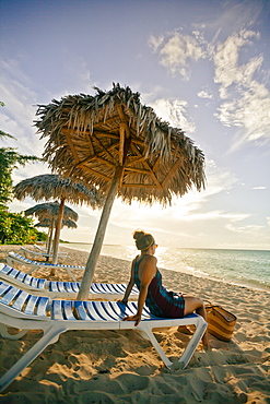 A young woman relaxing on the beach under a beach umbrella in Cayo Coco, Cuba