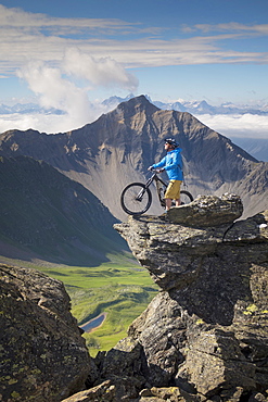 Mountain Biker Standing On Top Of Rock Near The Weisshorn In Switzerland