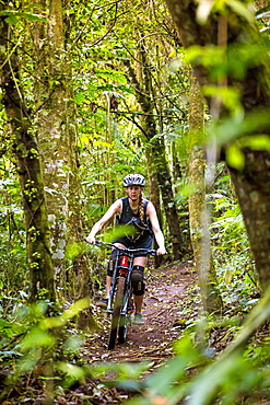 Female Mountain Biker Riding In Forest Trail Of Bali, Indonesia