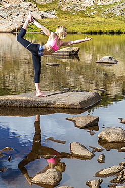 An Young Athlete Woman Practices Yoga On A Lake