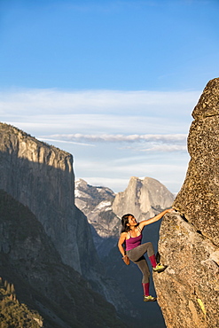 Female Climber Climbing On Rock In Yosemite With El Capitan And Half Dome In Background