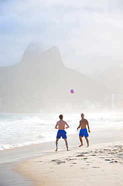 Two Men Playing Soccer In The Surf On Ipanema Beach, Rio De Janeiro, Brazil