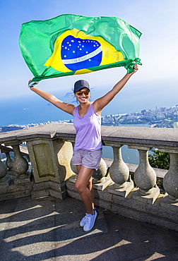 Woman holding Brazilian flag above Rio de Janeiro