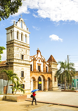 A Woman With Umbrella And Walking Across Historic Stone Church On A Sunny Day