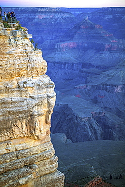 Tourists gather on the South Rim of the Grand Canyon at a viewpoint to view the sunset.