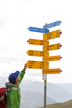 A hiker is looking at a sign post near Verbier. He is on his way on the Haute Raute, a classic multi day hike from Chamonix to Zermatt.